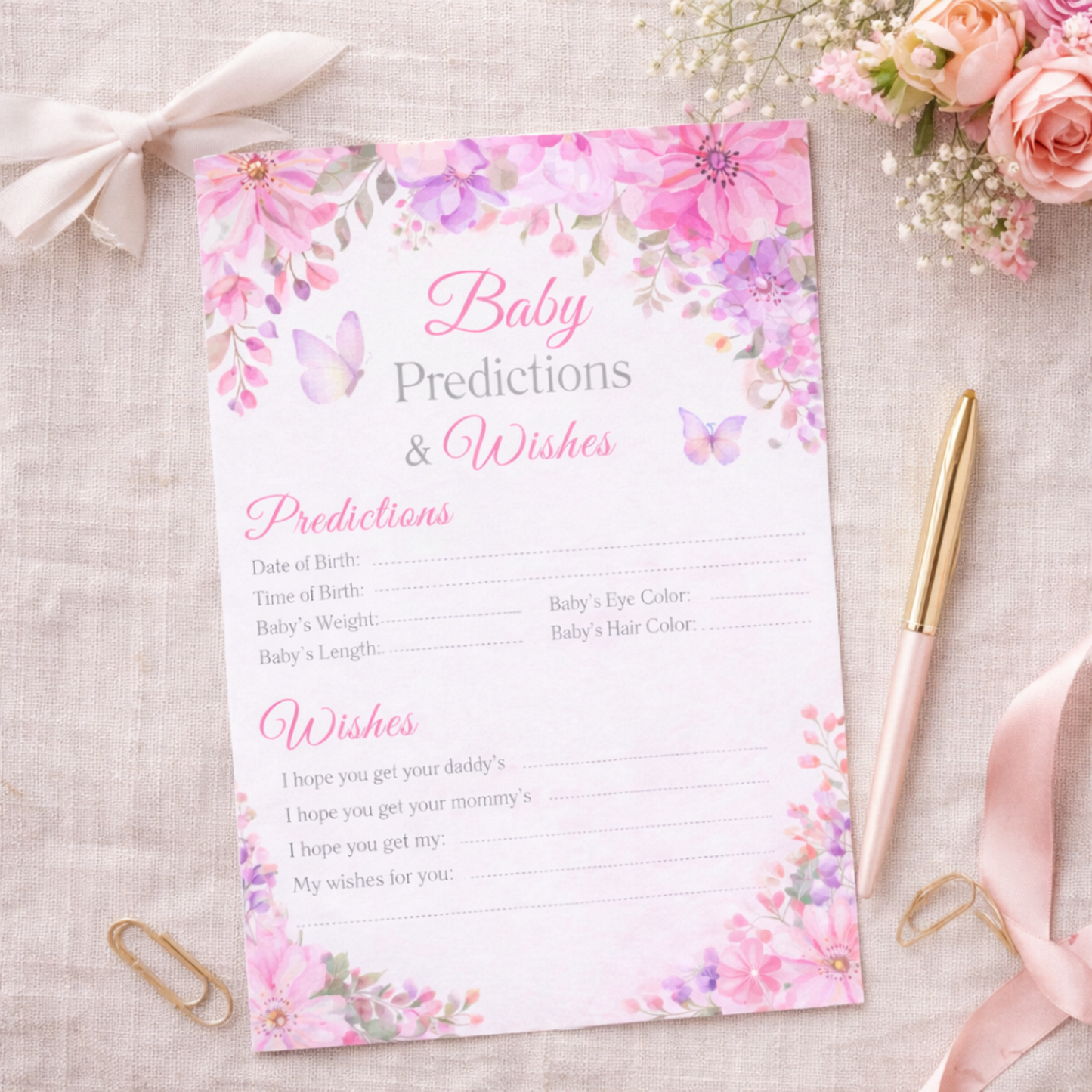 Baby predictions and wishes card with floral design on a textured surface with flowers and a pen.
