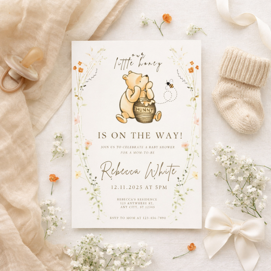 Baby shower invitation with Winnie the Pooh design, surrounded by baby items on a light background.