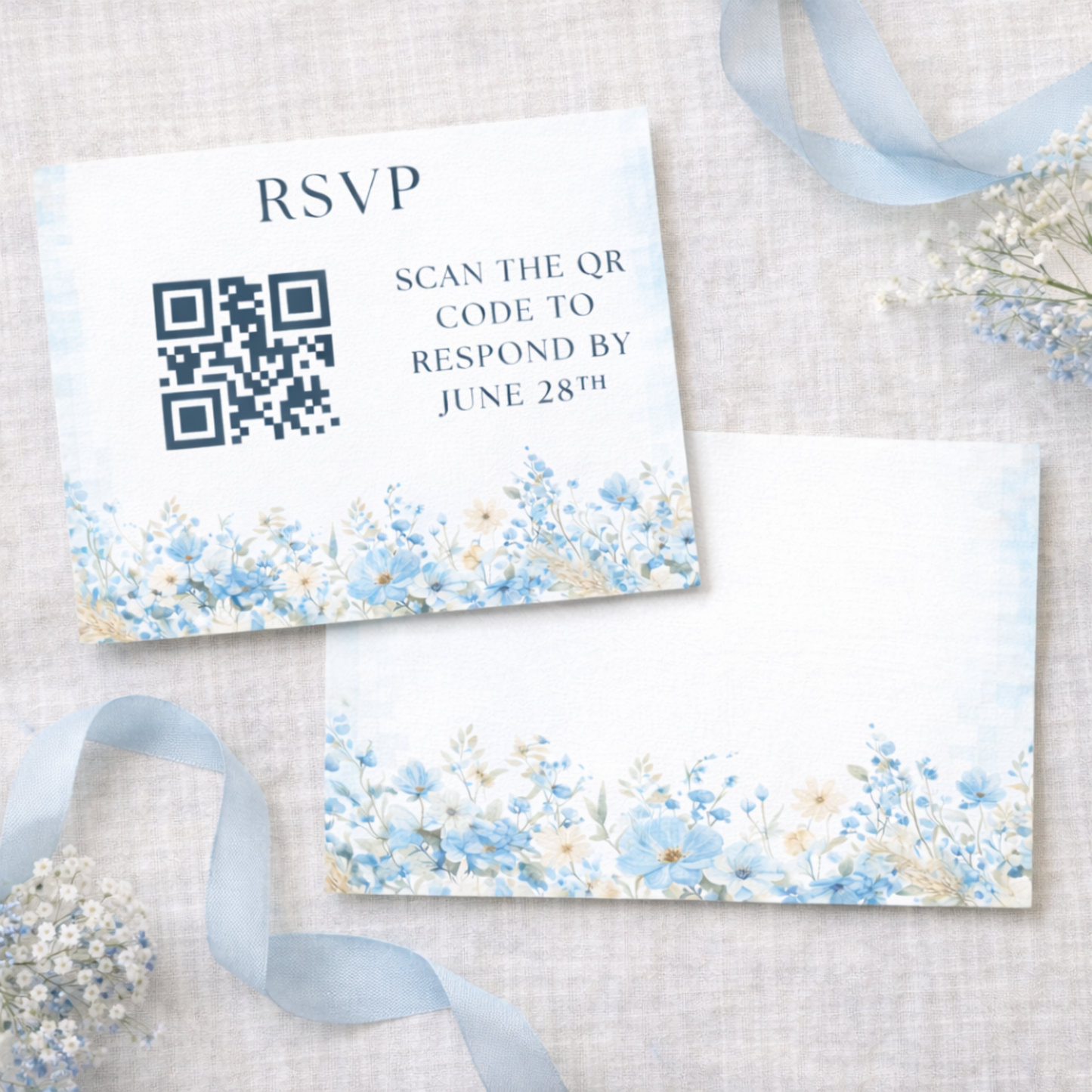 Baby shower RSVP card with QR code and floral design on a textured surface with ribbons and flowers.