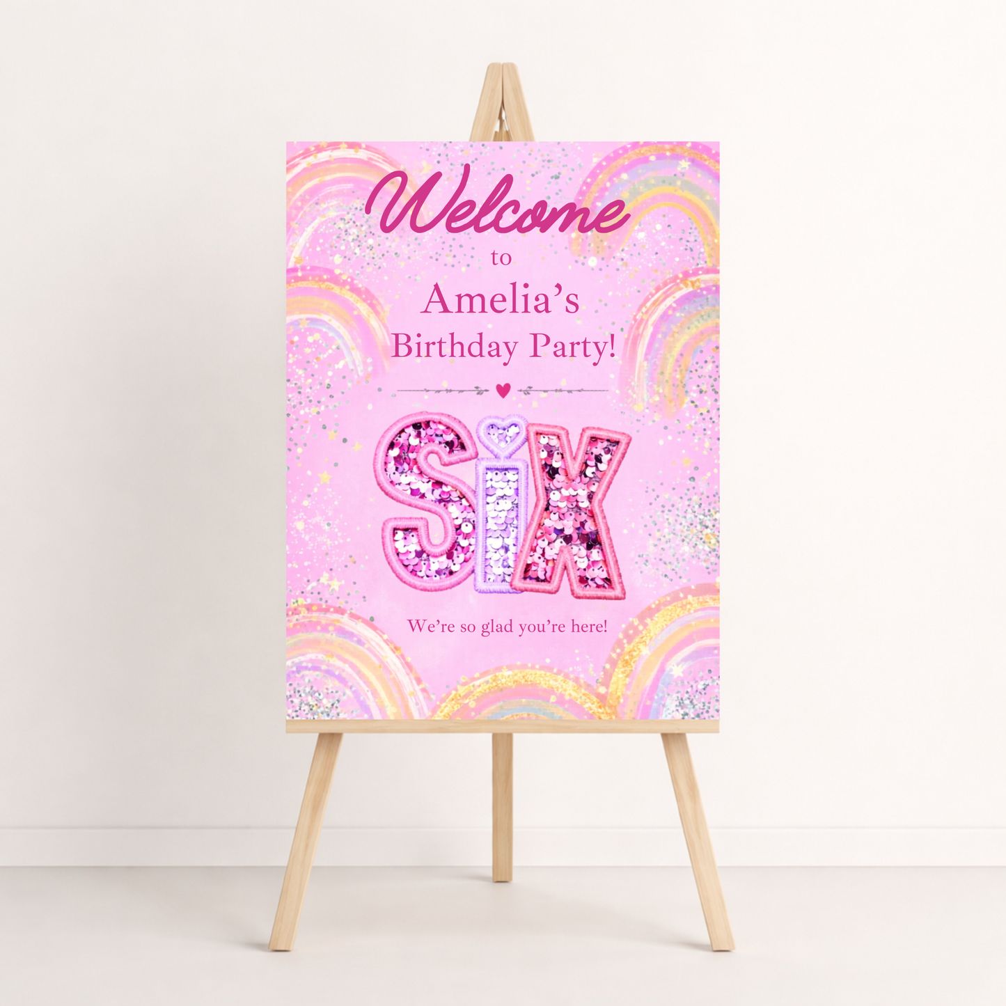 Birthday party sign with pink and rainbow design on a stand against a white background