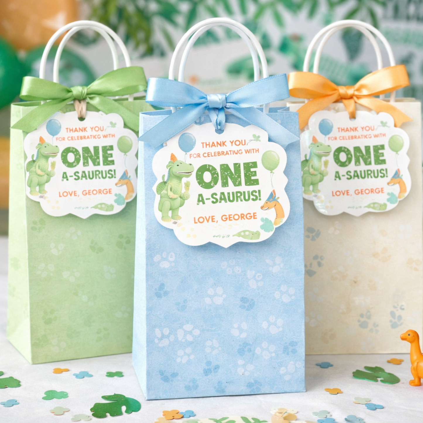 Three gift bags with dinosaur-themed tags on a surface with greenery in the background.