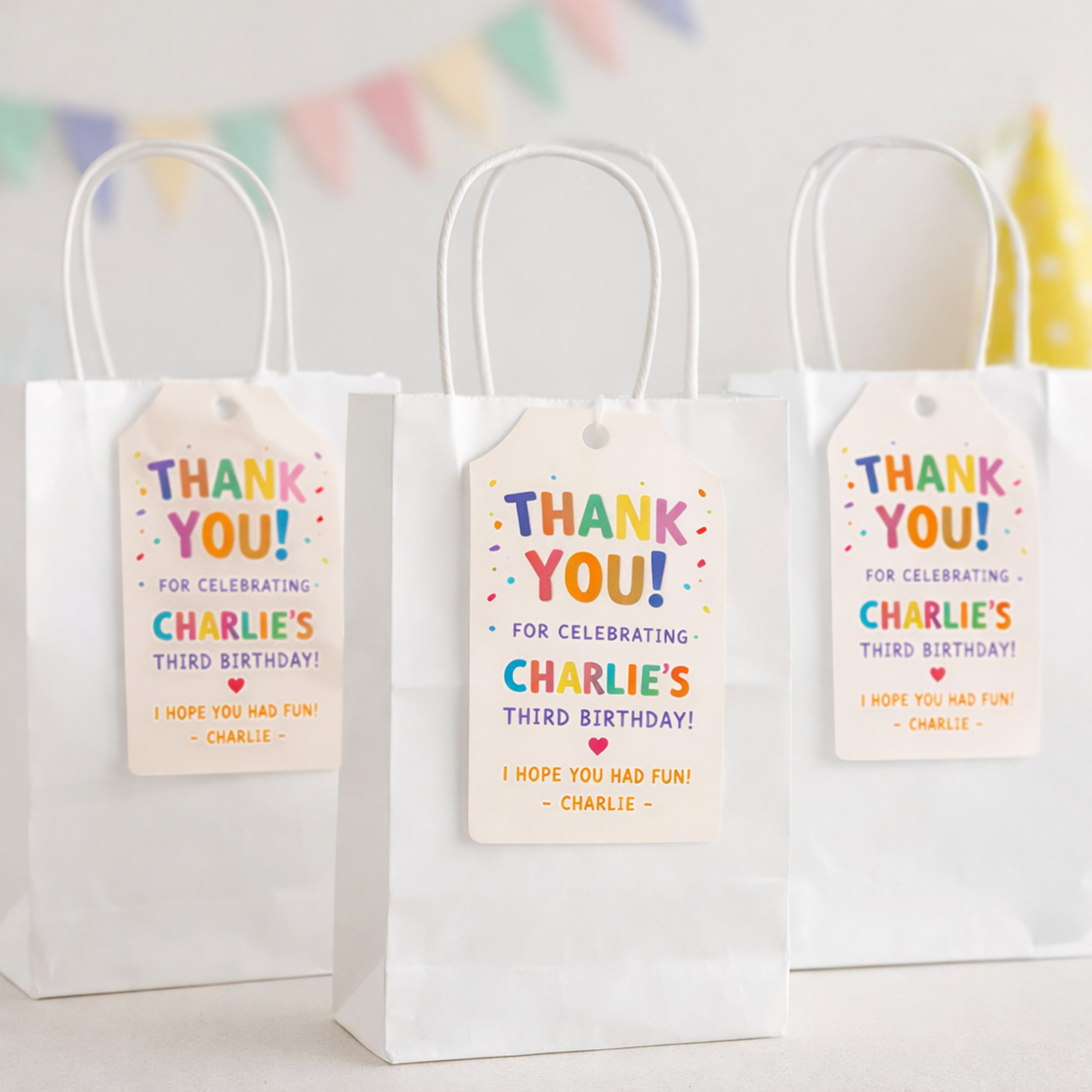 Three white gift bags with colorful 'Thank You!' tags for a birthday celebration.